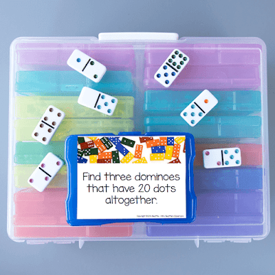 Photo of task card and dominoes on top of large container of task card bins.