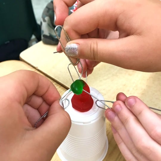 Photo of students using paper clips and gummy LifeSavers to "Save Fred" in a team-building activity.