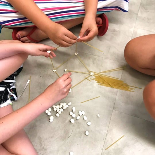 Students using spaghetti sticks and mini marshmallows to build a structure